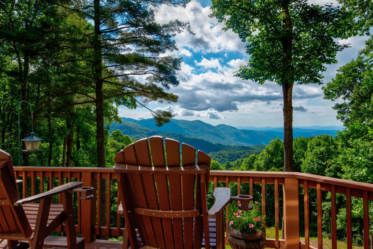 A peaceful setting with Adirondack chairs arranged to face a stunning mountain view, surrounded by lush greenery. The image exudes tranquility and opportunities for socializing, relaxing, or soaking in sunrise and sunset moments as a family.