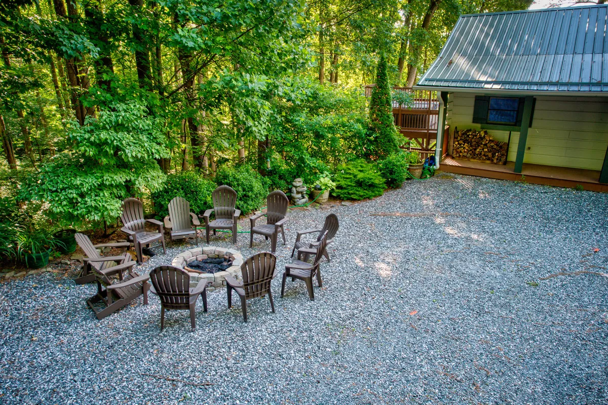 This image features a relaxed outdoor fire pit area with Adirondack chairs and lush greenery, set against the cozy backdrop of the cabin. The fire pit is the central gathering point, surrounded by nature, perfect for evenings spent roasting marshmallows, storytelling, or stargazing.